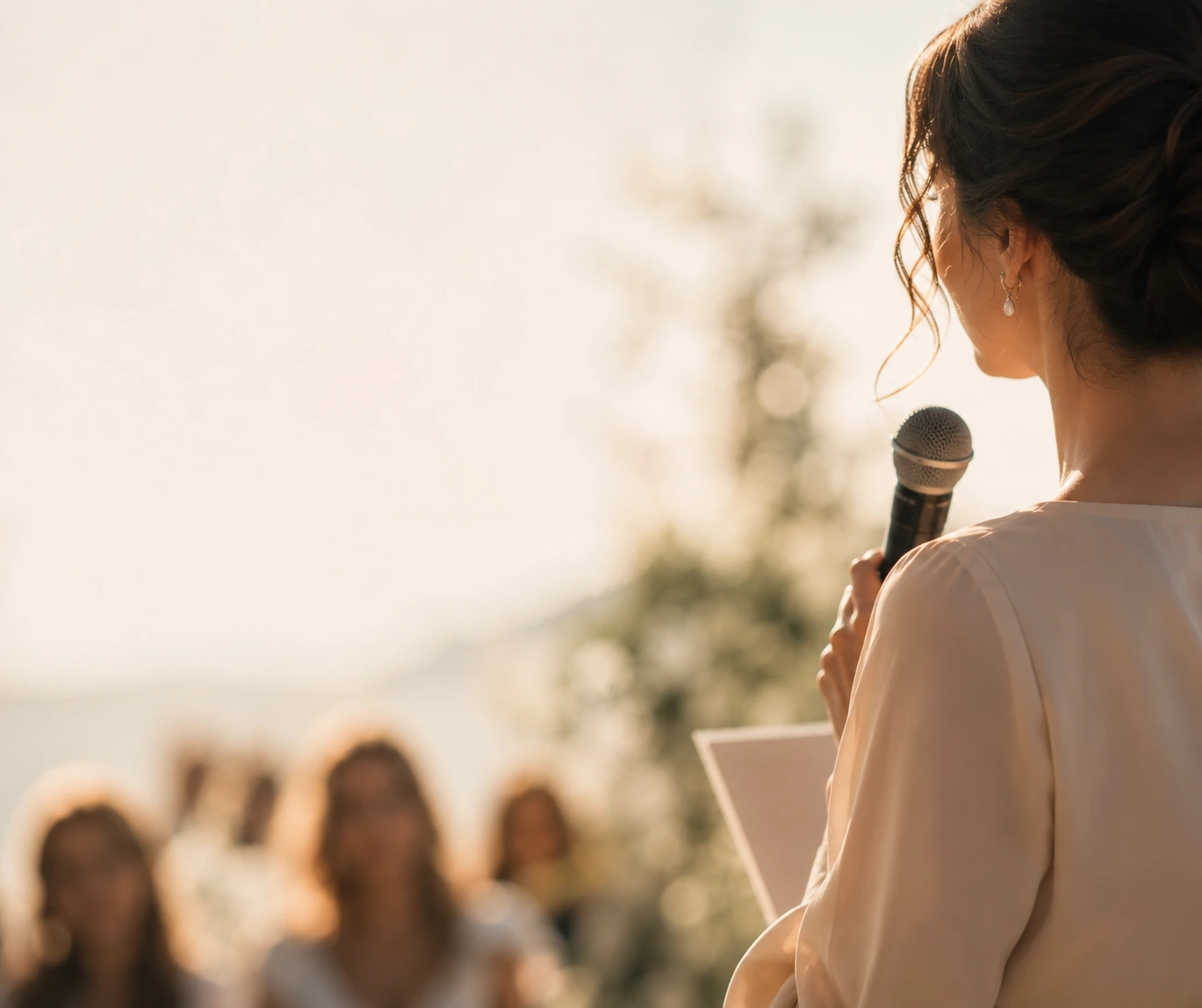 Celebrant addressing wedding guests outdoors with microphone